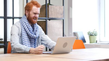 Dizüstü bilgisayarda çalışan sinirli sinirli sakallı adam