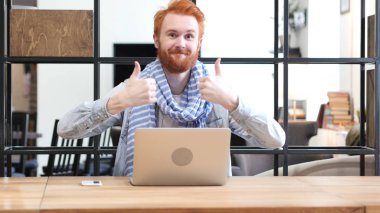 Başparmak yukarıya dizüstü bilgisayarda çalışan adam tarafından