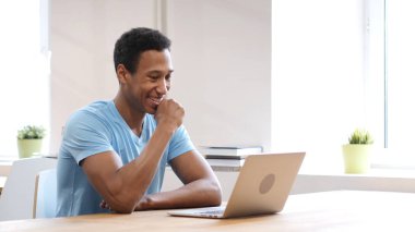 Başarılı siyah adam dizüstü bilgisayarda çalışırken mutlu