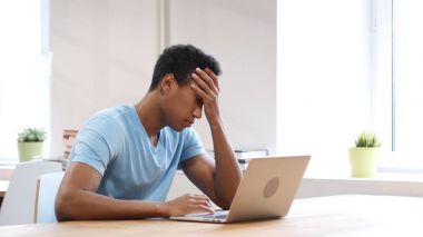 Baş ağrısı, yorgun genç dizüstü bilgisayarda çalışan adam siyah.