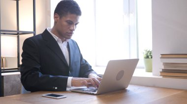 Siyah iş adamı dizüstü bilgisayarla çalışıyor