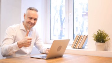 Başparmak yukarı orta yaş dizüstü bilgisayarda çalışırken adam tarafından