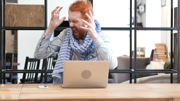 Разочарованный человек кричит, работает над ноутбуком в офисе — стоковое фото