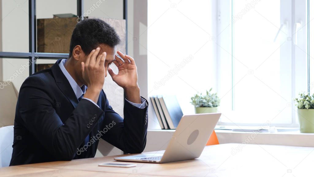 Pensive Black Man Thinking and Working on Laptop