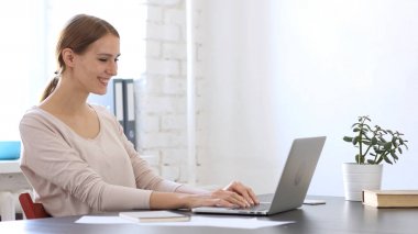 Gülümseyen güzel kadın ofiste dizüstü bilgisayarda çalışma