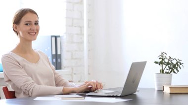 Gülümseyen yaratıcı kadın ofiste kamera bakıyor