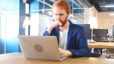 Düşünme ve dizüstü bilgisayar, kırmızı tüyler çalışan adam