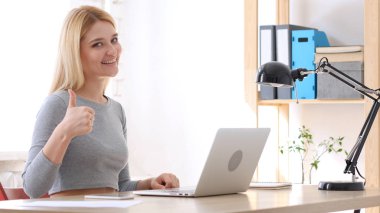 Başparmak yukarıya, kadın ofiste otururken el hareketi