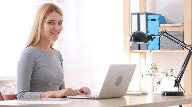 Genç sakin ol kadın seyir kamera Laptop üzerinde çalışma sırasında