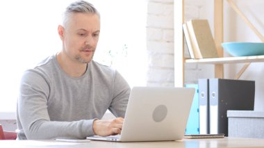 Ofiste dizüstü bilgisayarda çalışan adam kızgın orta yaşlı