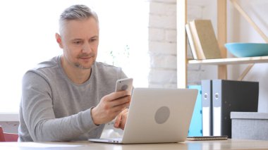 Orta yaşlı adam akıllı telefon, kullanarak kısa mesaj