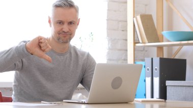 Başparmak aşağı orta tarafından dizüstü bilgisayarda çalışan adam yaşlı