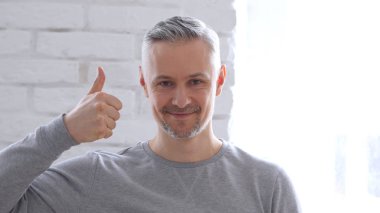 Ofiste oturan adam başparmak yukarıya tarafından orta yaşlı