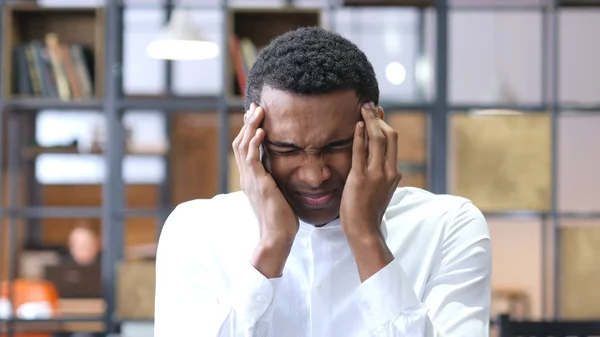Cansado hombre negro frustrado con dolor de cabeza en la oficina —  Fotos de Stock