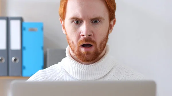 Choque, hombre maravilla con el pelo rojo que trabaja en el ordenador portátil —  Fotos de Stock