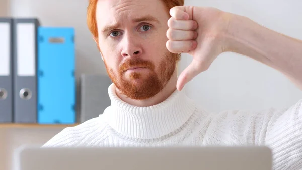 Daumen runter von einem Mann mit roten Haaren und Bart, der am Laptop arbeitet — Stockfoto