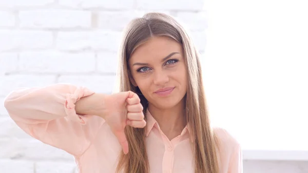 Daumen runter von einer jungen Frau, die im Büro in die Kamera schaut — Stockfoto