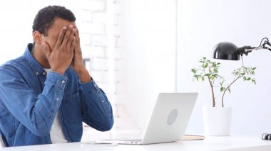 Yüzünü hayal kırıklığı içinde saklanıyor, iş yerinde Afro-Amerikan adam üzgün