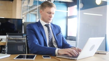 Onun ofisinde çalışan erkeğin dizüstü bilgisayar yazmaya