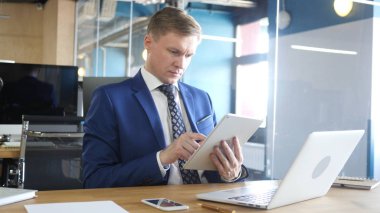 Genç işadamı Ofis Masası tarafından otururken tablet bilgisayar kullanarak