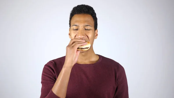 Prendre une bouchée de hamburger, jeune homme afro-américain manger un hamburger — Photo