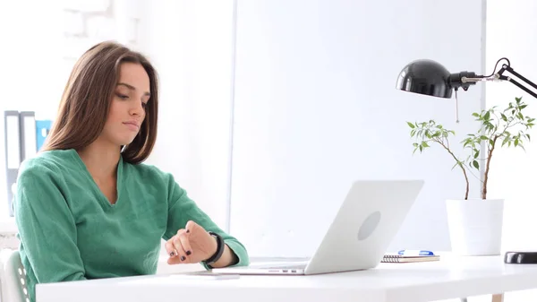 Frau beobachtet die Zeit während sie im Büro wartet — Stockfoto