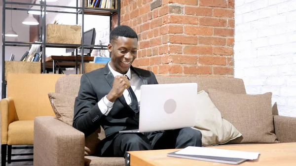 Empresario afroamericano animando el éxito, trabajando en el ordenador portátil —  Fotos de Stock