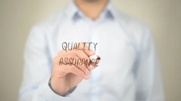 Garantia de qualidade, homem escrevendo na tela transparente — Fotografia de Stock