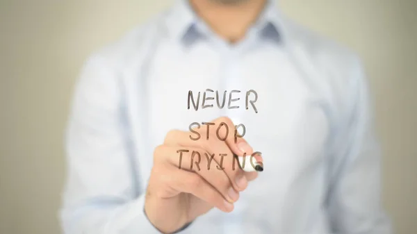 Never Stop Trying, hombre escribiendo en pantalla transparente — Foto de Stock