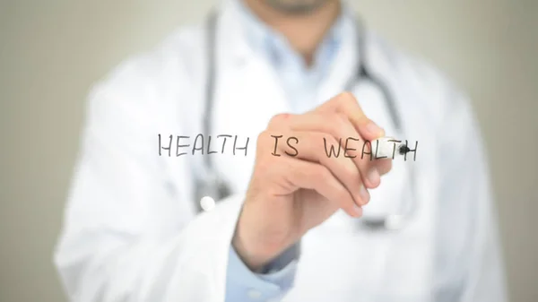 Gesundheit ist Reichtum, Arzt schreibt auf transparentem Bildschirm — Stockfoto