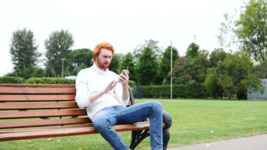 Adam bankta oturan Smartphone kullanarak Successs için heyecanlı