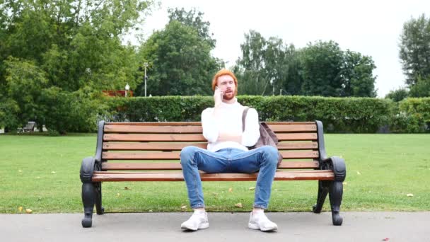 Hablando por teléfono, hombre sentado en el parque — Vídeos de Stock