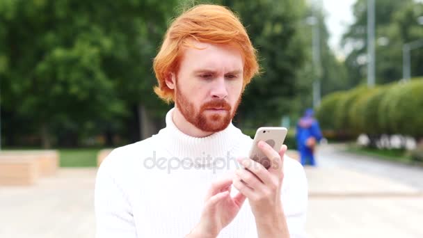 スマート フォンを使用したオンラインの閲覧、赤い毛、屋外を持つ男 — ストック動画