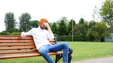 Baş ağrısı, genç adam, kırmızı saç ve sakal üzgün jest