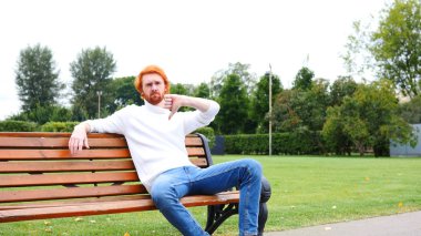 Başparmak aşağı Park, kırmızı saç ve sakal bankta oturan adam tarafından