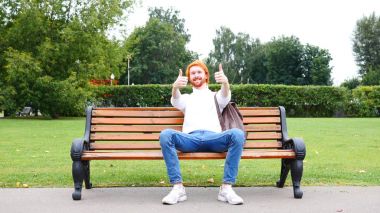 Her iki el başparmak yukarıya Park, kırmızı saç ve sakal bankta oturan adam tarafından