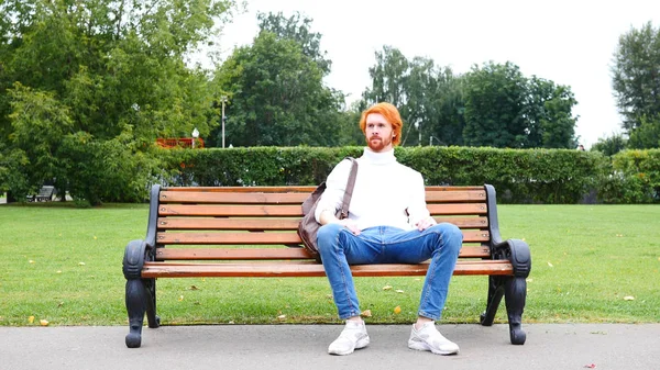 Beard Man sitter på bänken i parken, röda hårstrån — Stockfoto