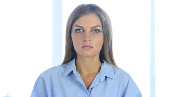 Серьезная молодая женщина смотрит в камеру в офисе — стоковое фото