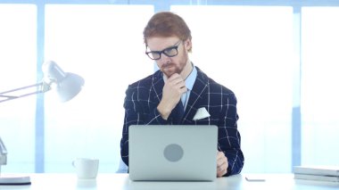 Düşünme ve dizüstü bilgisayarda çalışan Kızıl saçlı dalgın adam