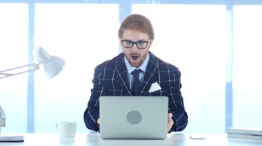 Kızıl saçlı işadamı hayran, dizüstü bilgisayarda çalışan adam şaşırttı