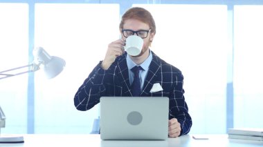 Rahatlatıcı ve iş yerinde kahve içme Kızıl saçlı işadamı