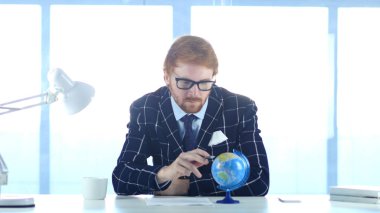 Kızıl saçlı işadamı okuma dünya küre dikkat