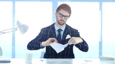 Öfkeli kızıl saçlı adam yırtılma gazetelerde ofis, iş başarısız