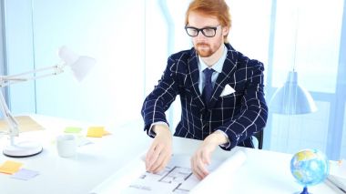 Kızıl saçlı mimari mühendis açılış Blueprint ofiste masa