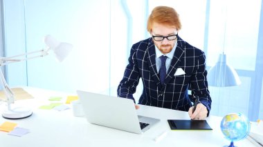 Bir bilgisayar için çizim tabletiyle çalışan Kızıl saçlı tasarımcı