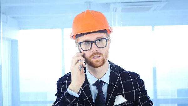 Beard arkitektoniska ingenjör pratar telefon, delta i samtal på jobbet — Stockfoto