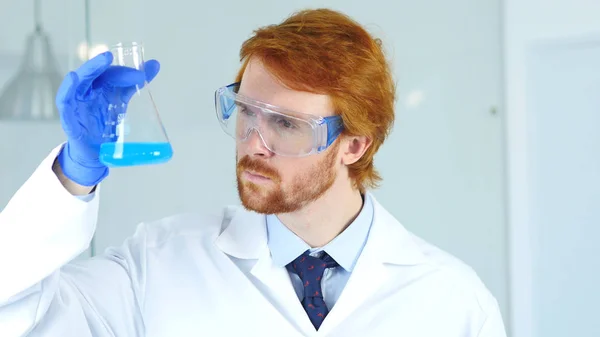 Vědec, lékař při pohledu na modrý roztok v baňce v laboratoři — Stock fotografie