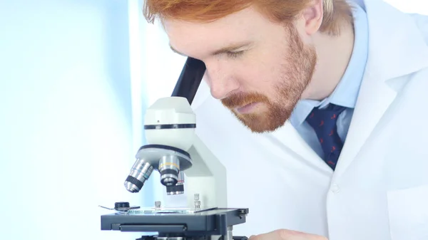 Redhead chemik, vědecký Reseacher pracuje na mikroskopem v laboratoři — Stock fotografie