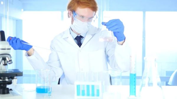 Científico mirando la reacción que ocurre en el frasco en el laboratorio —  Fotos de Stock