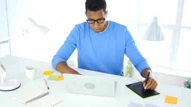 Afro-Amerikan yaratıcı tasarımcı çalışma ile grafik tablet üstünde Laptop